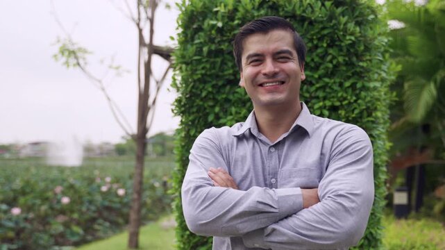 Portrait of happy handsome Caucasian businessman in a shirt standing smiling and arms crossed while looking at the camera outdoors with cheerful while relaxing in the lotus garden at a public park. 