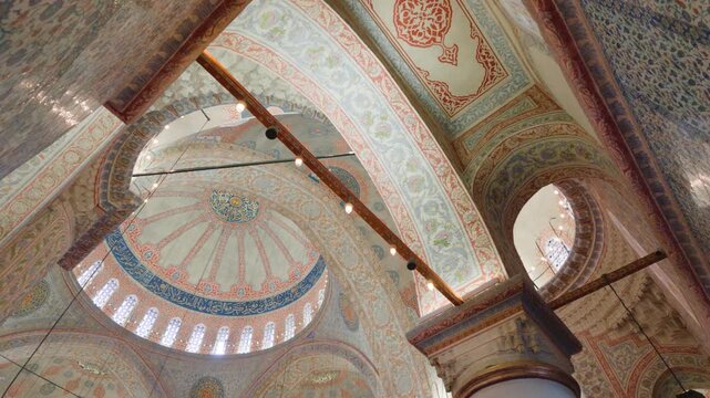 View of the intricate tile work and ornate dome interior of the historic Sultan Ahmet Cami in Fatih, Istanbul, Turkiye.