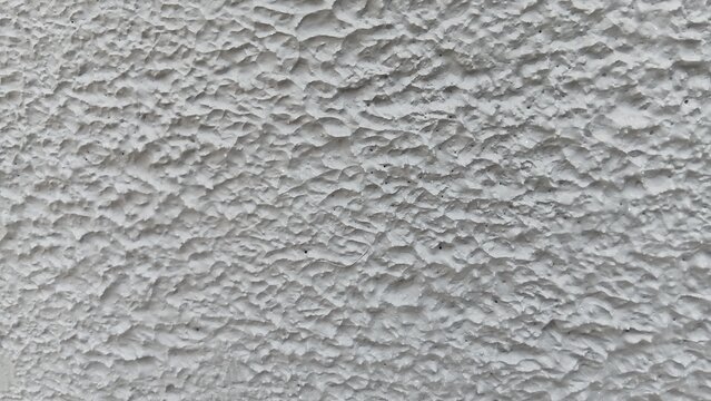 Close-up abstract white textured surface with rough, uneven layers and natural irregular patterns. Soft lighting emphasizes the detailed relief, creating a minimalist monochrome background suitable fo