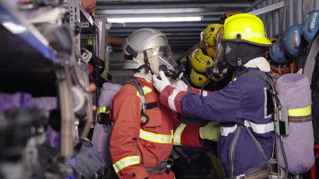 Firefighters checking safety breathing mask for buddy at station