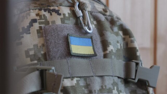 Close up of soldier attaching Ukrainian flag velcro patch onto military bag