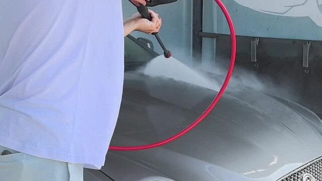 Car wash spraying soapy water on a modern vehicle exterior, auto detailing and vehicle maintenance concept