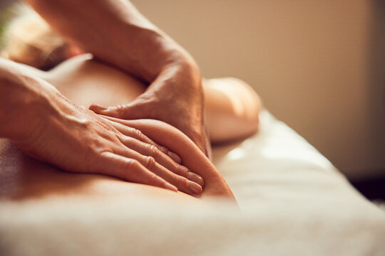 Therapist hands giving back massage on spa treatment table