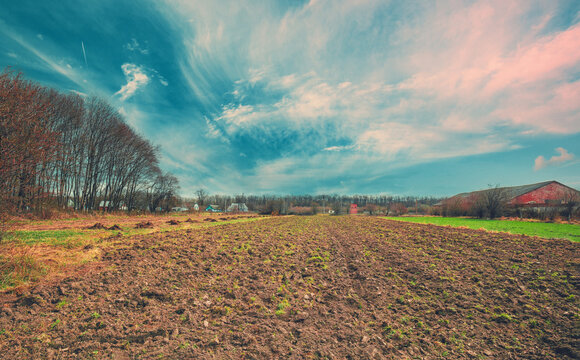 View of an arable field with a partly cloudy sky. Rural landscape in early spring