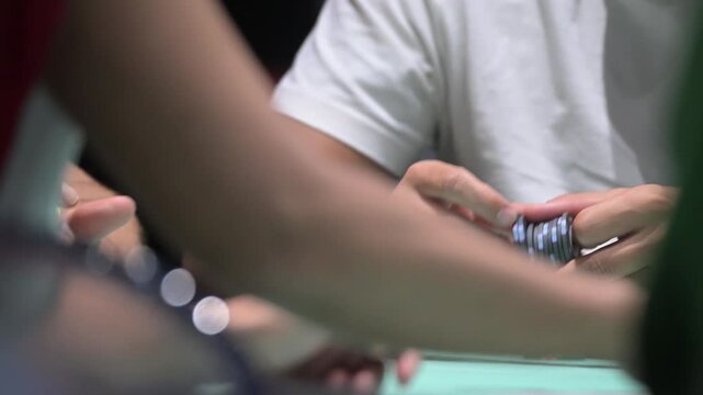 View of hands playing poker with chips on a green table, Portugal.
