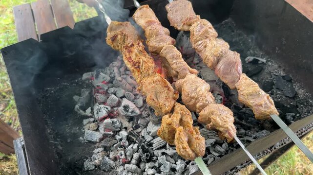 Shashlik on the grill a skewer with pieces of pork is being turned over the coals. High quality 4k footage