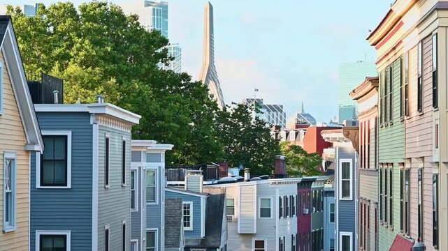 View of the iconic architecture of Boston at Charlestown with its colorful homes and the famous Zakim Bridge in the background on a sunny morning.