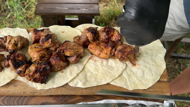 Pieces of hot, grilled shashlik on flatbread a hand slides the juicy meat off the skewer. High quality 4k footage
