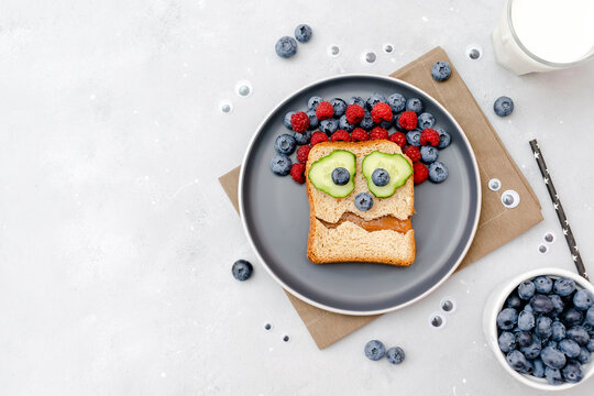 Funny scary monster halloween sandwich toast bread with peanut butter.Kids child sweet dessert breakfast lunch food with blueberry,raspberry,bats on gray background.