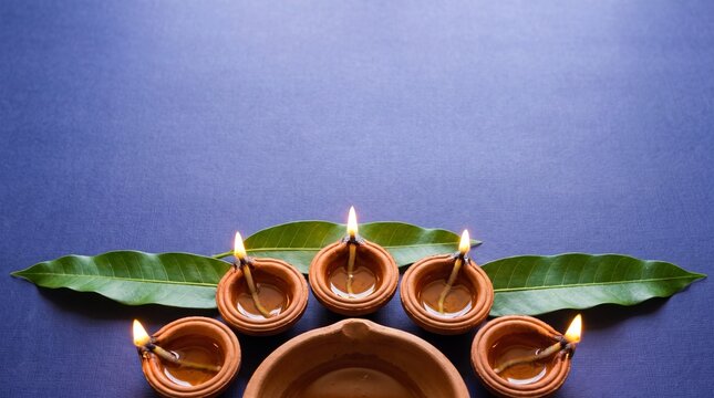 traditional oil lamps lit on green leaves against blue background for festive decoration
