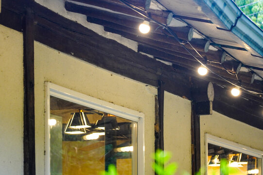 Rustic Building Exterior with Exposed Wooden Beams and Illuminated String Lights