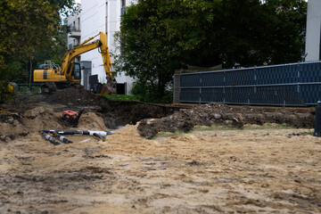 An excavator is working at a construction site featuring a trench and a foundation © Олеся Матвеева