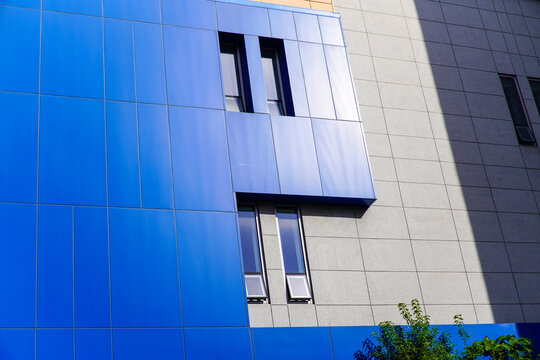Modern Building Facade with Contrasting Blue and Gray Panels and Reflective Windows