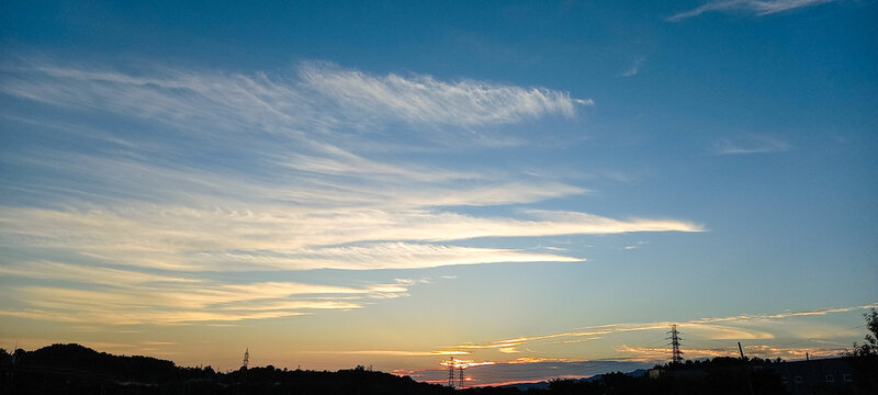 Dramatic Sunset Sky with Colorful Streaky Clouds over Silhouetted Hills and Power Lines