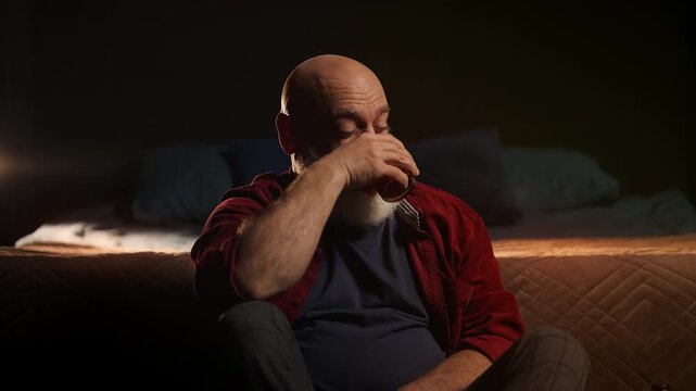 Lonely bearded man drinks liquor at home, struggling with midlife crisis