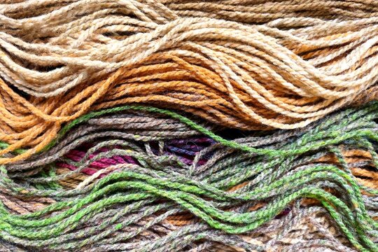 Detailed texture of natural earth-toned hand-dyed wool yarn strands for traditional weaving and knitting