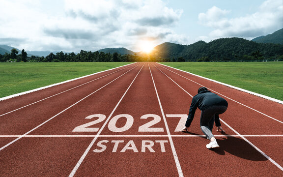 New year resolution 2027 concept. Word start 2027 on athletics track and athlete woman runner preparing to new year at sunset for challenge and beginning planning health and the goal to success.