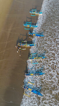 Drone shot of traditional Indonesian fishermen preparing wooden boats on Pujiharjo beach East Java