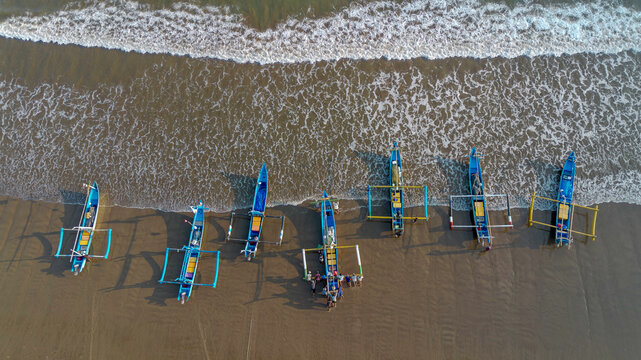 Drone shot of traditional Indonesian fishermen preparing wooden boats on Pujiharjo beach East Java