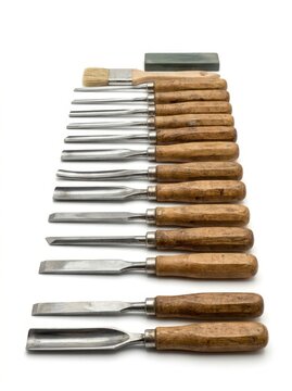 Wood carving chisels laid out with a brush and sharpening stone isolated on white background