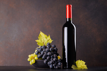Obraz premium Red wine bottle with a glass and basket of fresh grapes