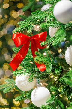 Red bow on Christmas tree with festive golden lights