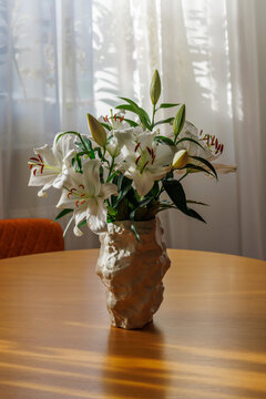 White Lily Flowers in Vase on Wooden Table