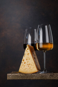 White and red wine glass with cheese on rustic table
