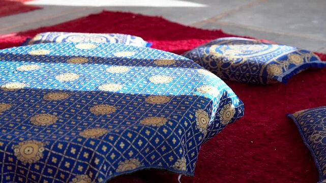 モロッコの赤い絨毯に並ぶ青と金の伝統的なクッション（Traditional Blue and Gold Cushions on Red Carpet, Morocco）
