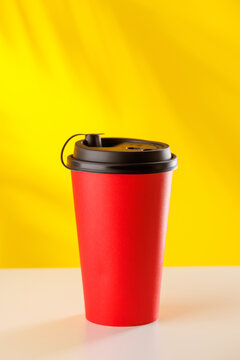 Red takeaway coffee cup on yellow background
