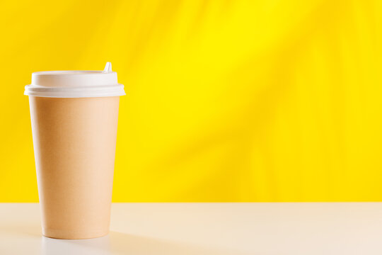 Disposable coffee cup on bright yellow background