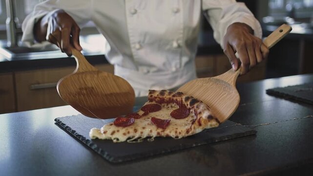 Sliding, chef in white coat lifting pepperoni slice at pass, paddles pulling cheese serving patrons