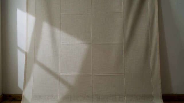 Tube releasing cream roller blind unrolling fabric down paneled studio wall showing window shadow