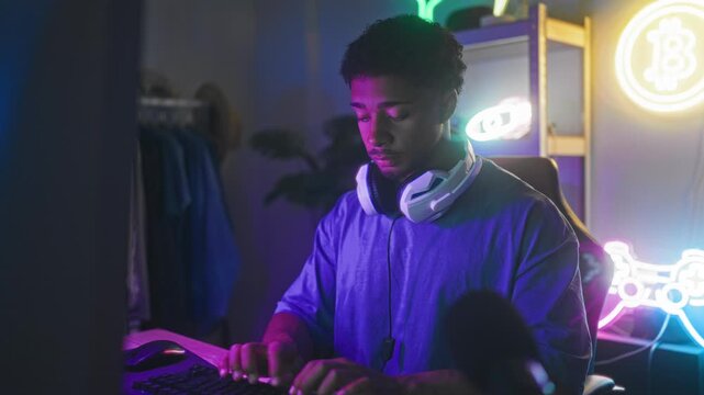 Man wearing headset typing on keyboard with hands on keys in studio while later giving thumbs up gesture; concentration success.