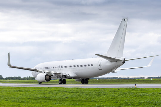 White passenger airliner taxiing at the taxiway at the airport in cloudy weather