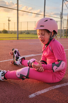 Little girl fall down from roller skates and cry in pain outdoor park