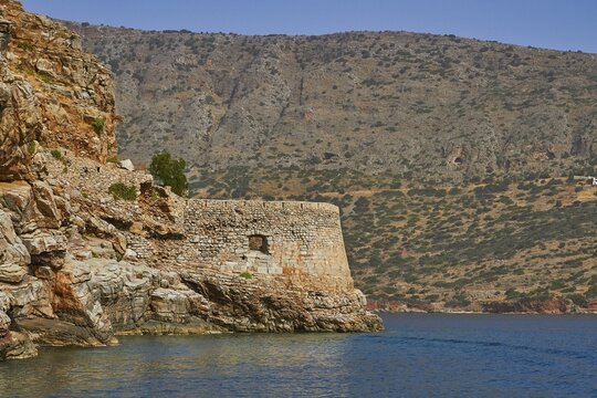 Ancient fortress in rocky coastal landscape surrounded by hilly terrain and calm blue waters, Venetian sea fortress, Leper Island, Spinalonga, Elounda Bay, Mirabello Bay, East Crete, Crete, Greek Islands, Greece