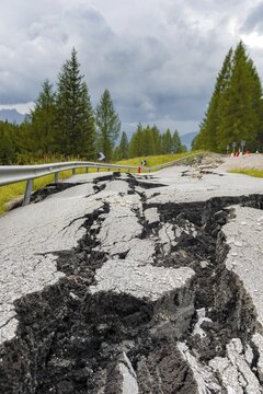 Broken road with cracks in the road surface, broken roadway of a mountain road, Belluno, Italy