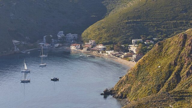 A picturesque coastal village with boats on a sunny evening, surrounded by mountains, southern tip, Mani Peninsula, Peloponnese, Greece