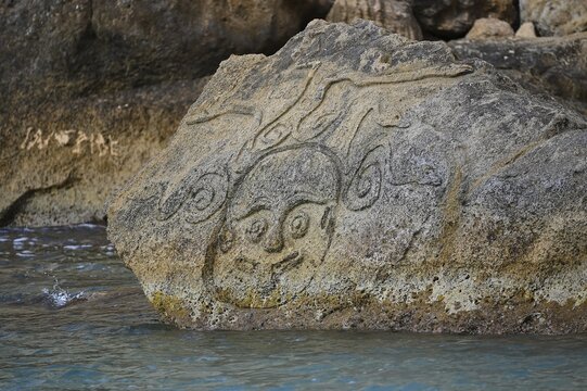 Red Beach, dream beach in the neighboring bay of Matala, a stone rock at the water's edge with an artistic face carving, Matala, Neolithic caves, former hippie paradise, central south coast, Crete, Greek islands, Greece