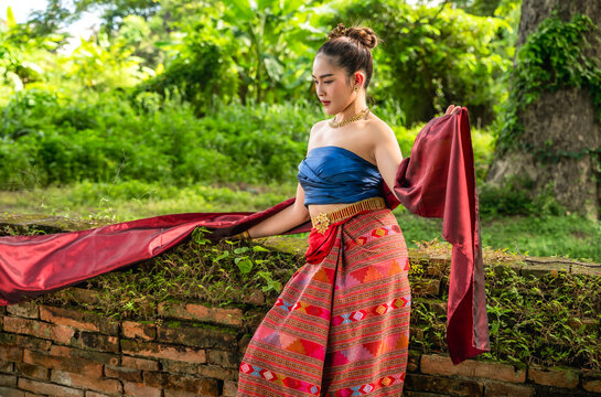Northern Thai Lanna woman wearing hand-weaving intricate folk patterns onto a cotton sinh skirt and sabai shawl traditional local attire standing in historical site environment