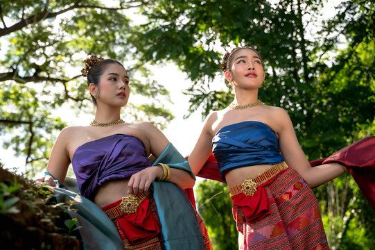 Northern Thai Lanna women wearing hand-weaving intricate folk patterns onto a cotton sinh skirt and sabai shawl traditional local attire standing in tropical greenery natural green environment