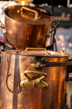 Copper pots displaying a hammered texture and shiny brass handles at a market