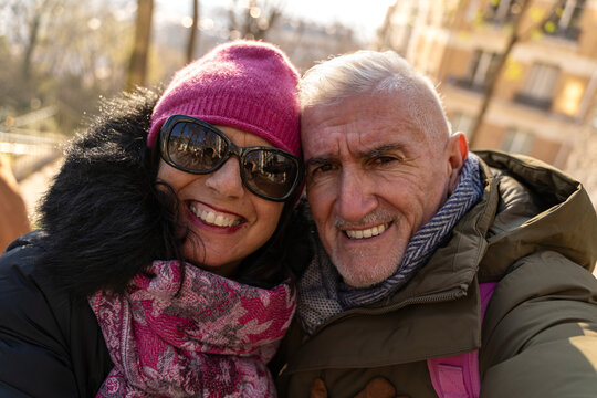 Senior couple smiling while taking selfie outdoors enjoying winter holiday