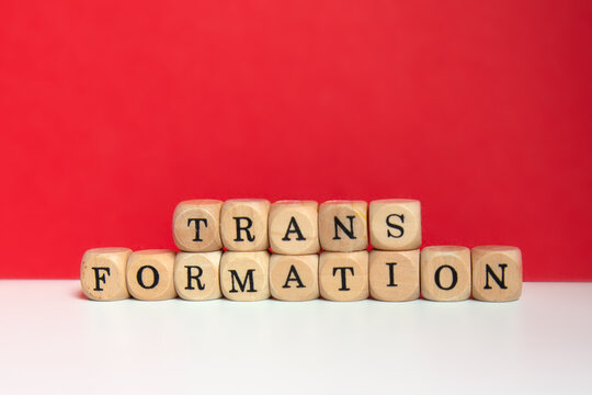 Transformation concept with word spelled on wooden blocks against red background;