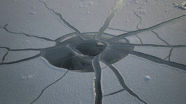 Sun warming ice ring lowering dome, widening cracks and exposing water on pond, fragment on rim