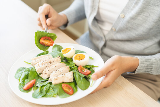 Diet Ketogenic, Low carb, Intermittent Fasting woman, girl holding fork to prick fresh vegetables or green salad at home. Nutrition food, low fat to good body, getting weight loss for healthy concept