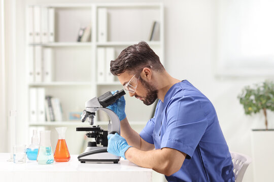 Lab technician sitting and looking through a microscope