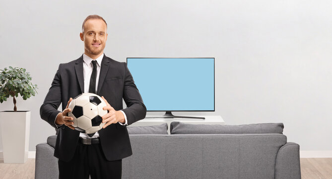 Smiling businessman in a suit holding a football
