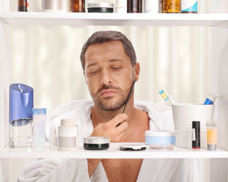 Man in a bathrobe in front of bathroom cabinet